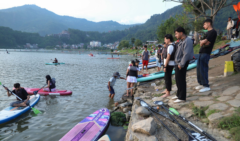 गर्मी छल्न फेवातालमा हेलिँदै पर्यटक, युवापुस्तामाझ लोकप्रिय बन्दै ‘स्ट्यान्ड अप प्याडल बोर्डिङ’ (तस्वीरहरू)